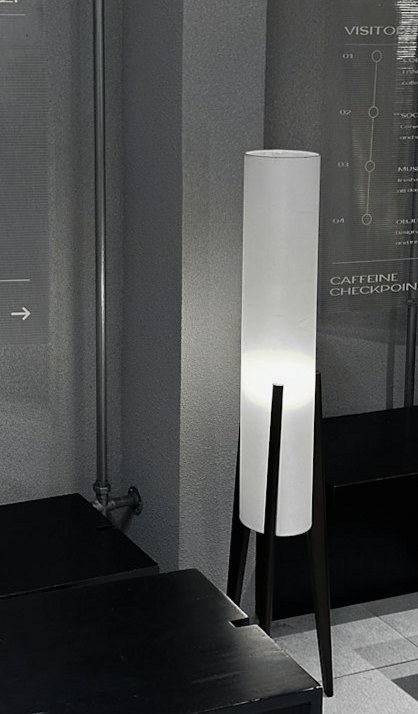 モノクロの室内に置かれた、白い筒状のフロアランプ